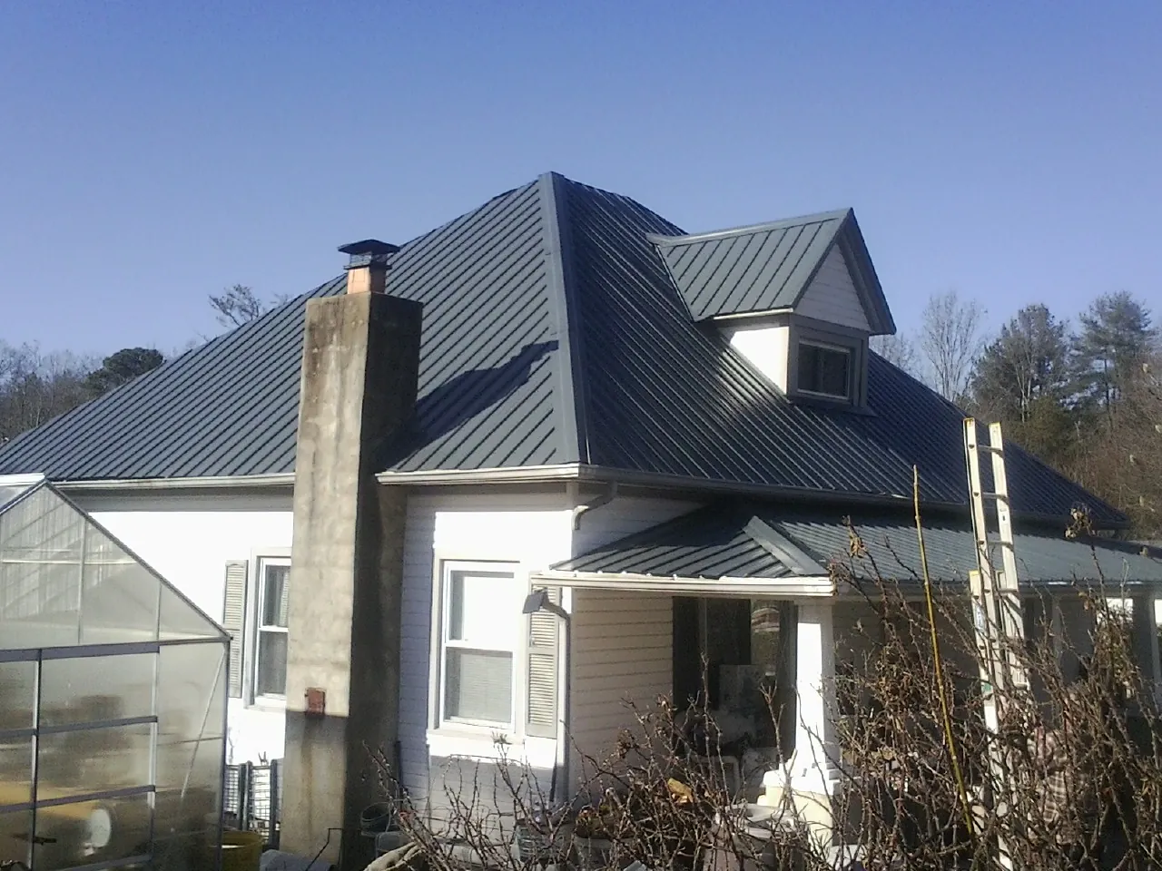 Dark blue standing seam metal roof on a white farmhouse with dormer — Slate & Tile Roof Repair by Roofing Brothers in New Palestine