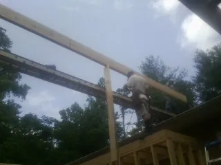 Carpenter setting a ridge beam over a new addition frame in New Palestine
