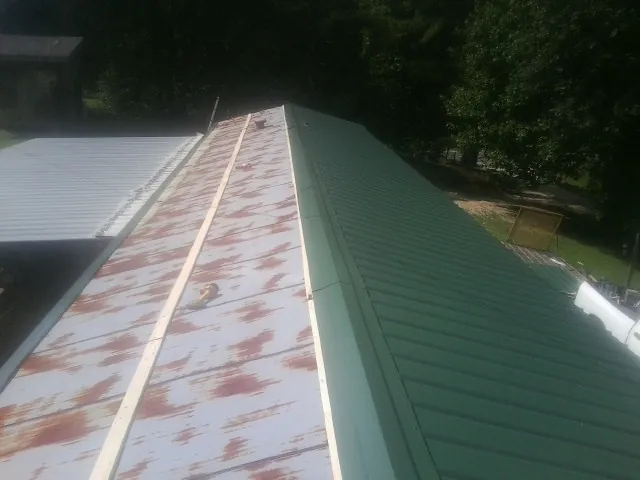 Old rusted panels beside newly installed green metal roofing — Wind Damage Roof Repair by Roofing Brothers in New Palestine