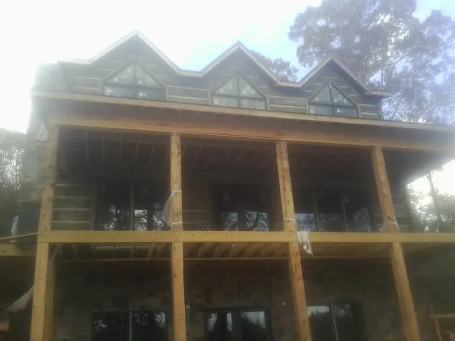 Dormers and porch framing on a large log home under construction — Roof Coating work by our crew in New Palestine