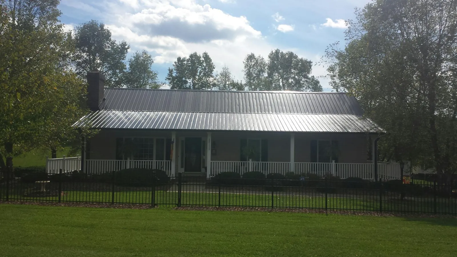 Gray metal roof on a brick ranch with a full width front porch — Gutter Guard Installation work by our crew in New Palestine