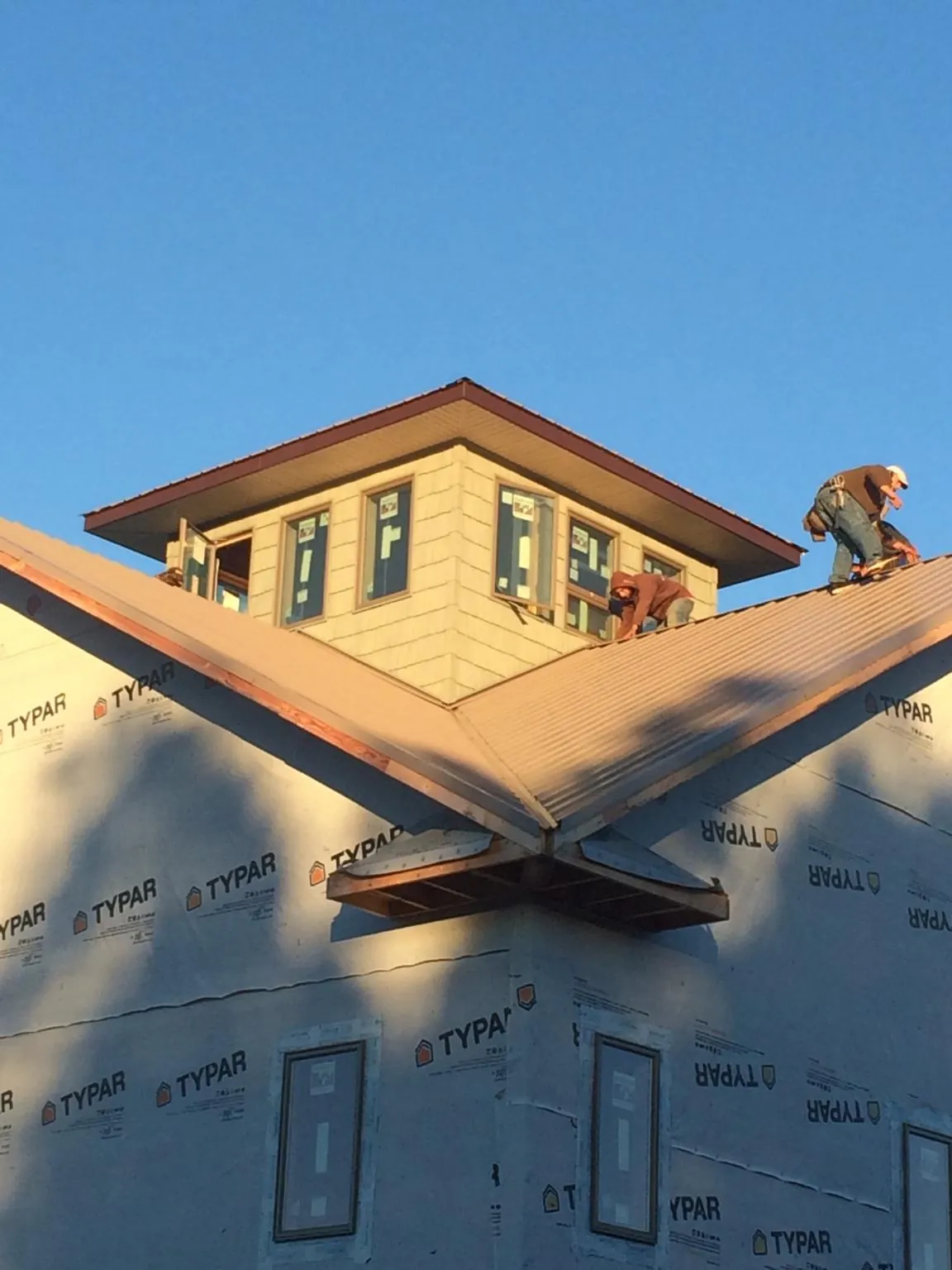 Roofers working around a rooftop cupola on a new metal roof at sunset — Roof Waterproofing in New Palestine by Roofing Brothers